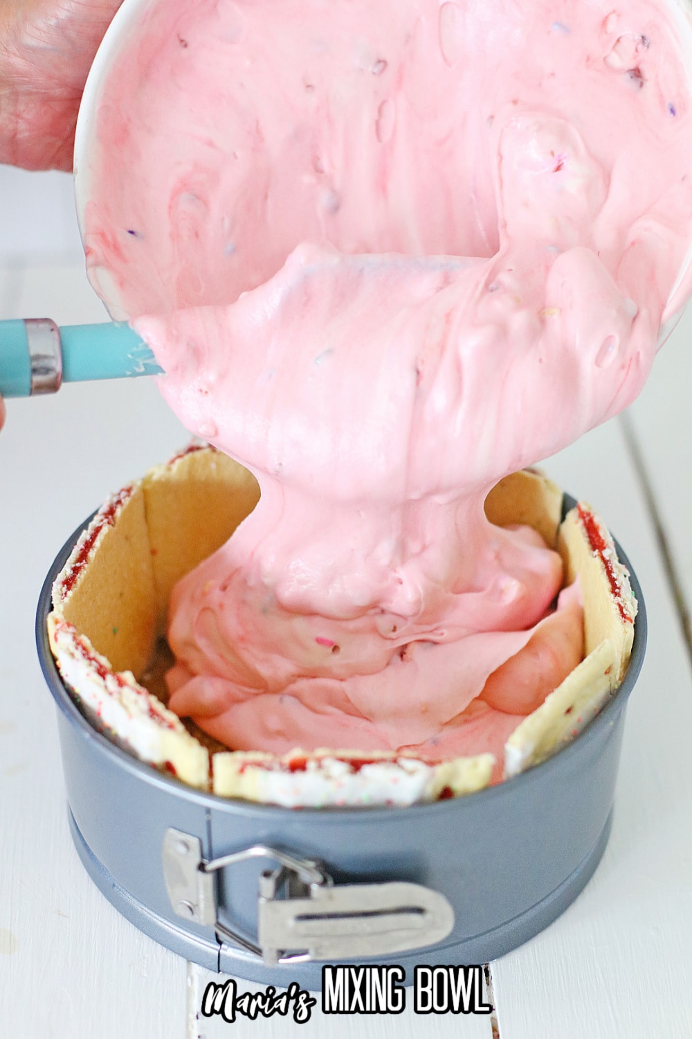 cheesecake batter being poured into a poptart lined springform pan.