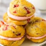 three strawberry shortcake sandwich cookies on a white plate