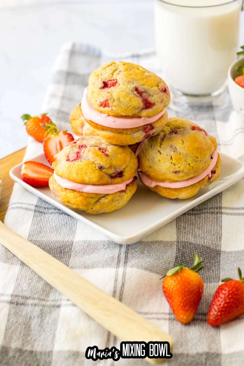 three strawberry shortcake sandwich cookies on a white plate