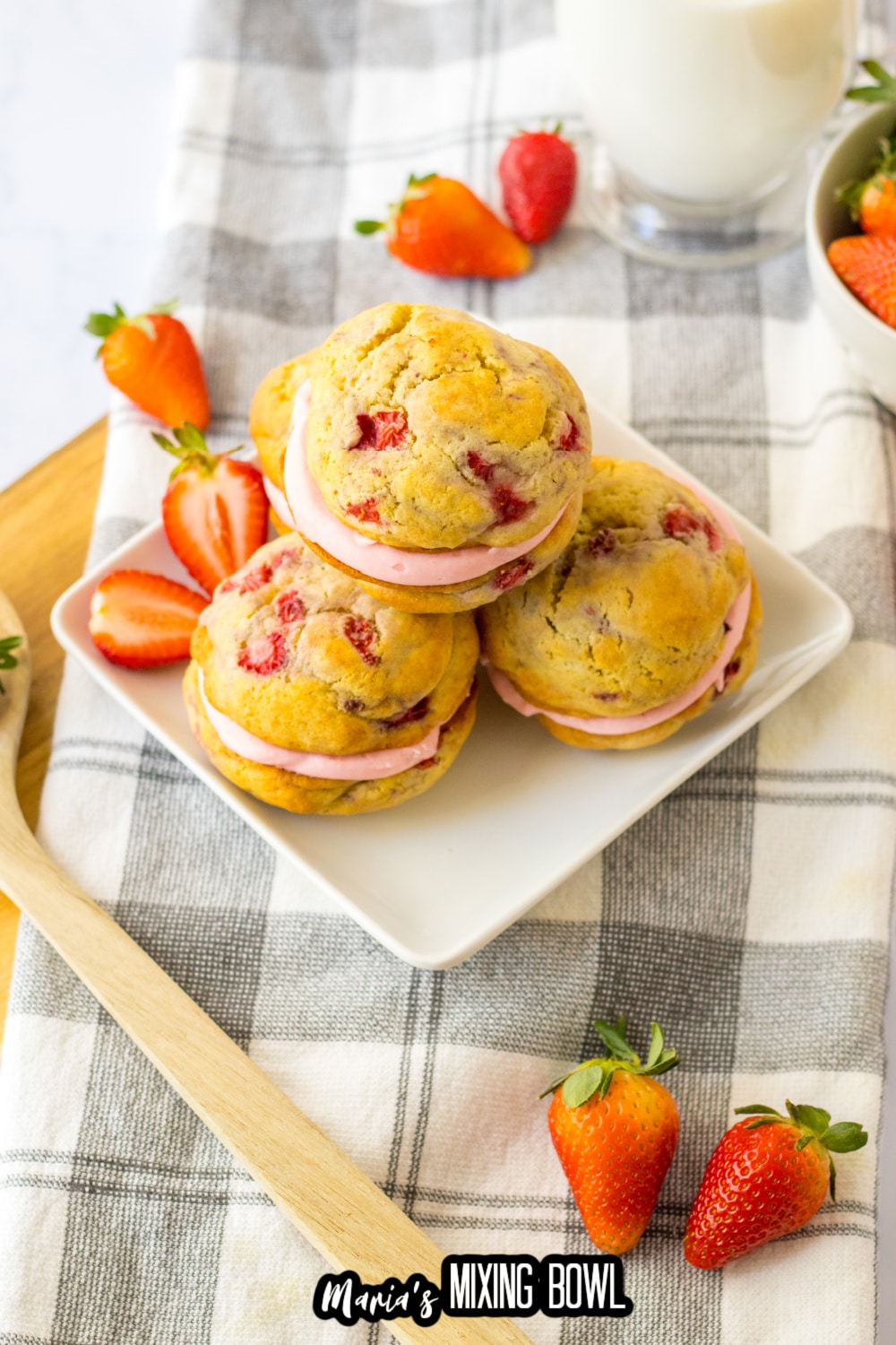 three strawberry shortcake sandwich cookies on a white plate