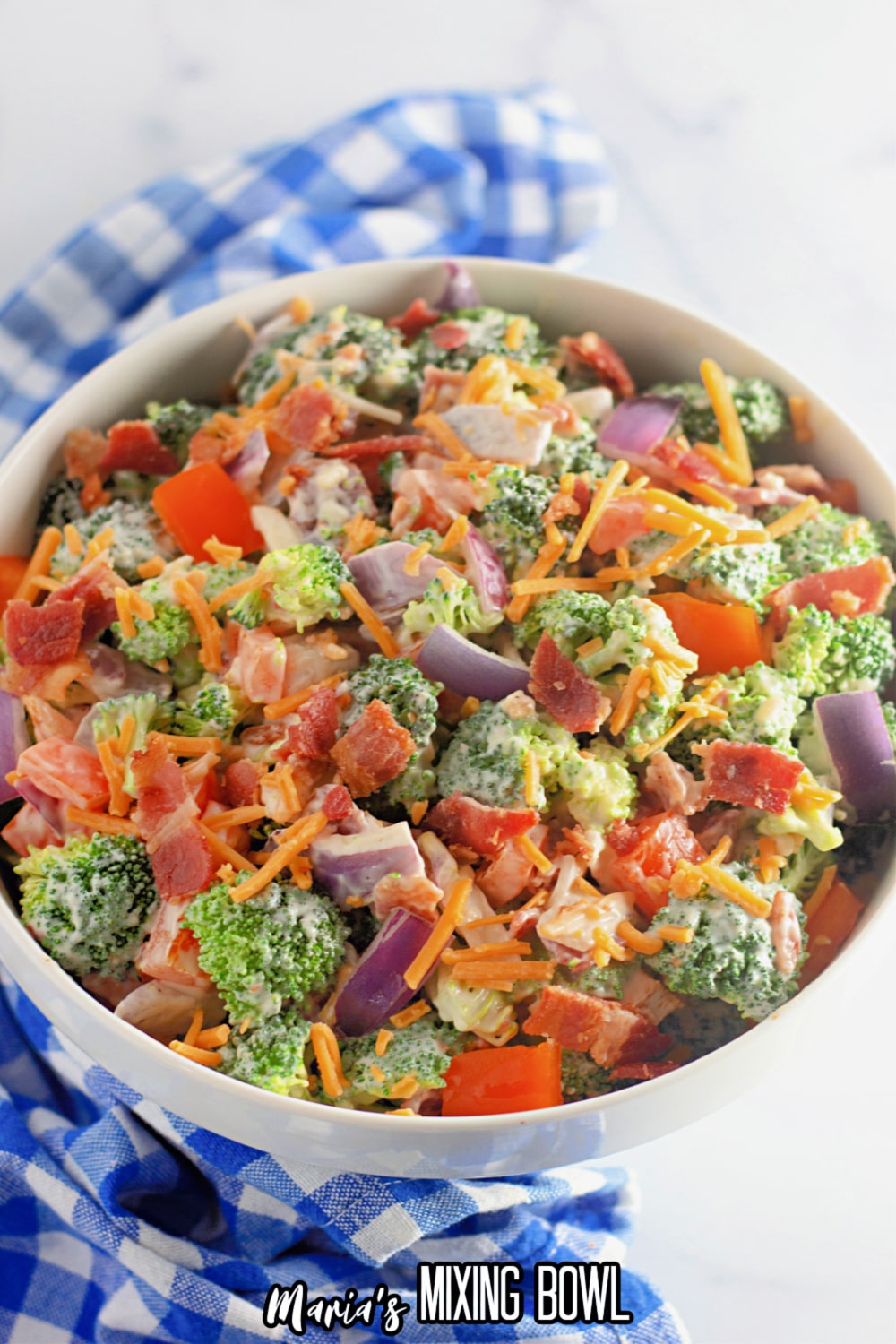 close up of a broccoli salad with almonds on a white background