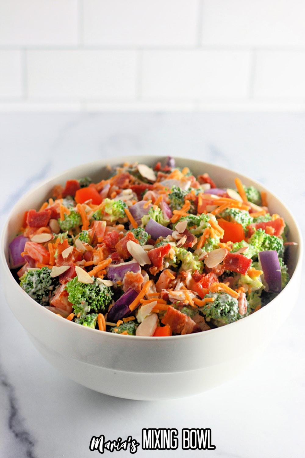 broccoli salad in a white bowl on a white marble background