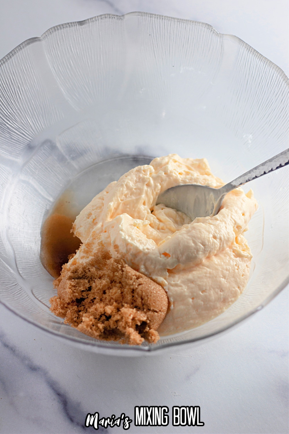 mayo, sugar, and vinegar being mixed in a glass mixing bowl with a sliver spoon