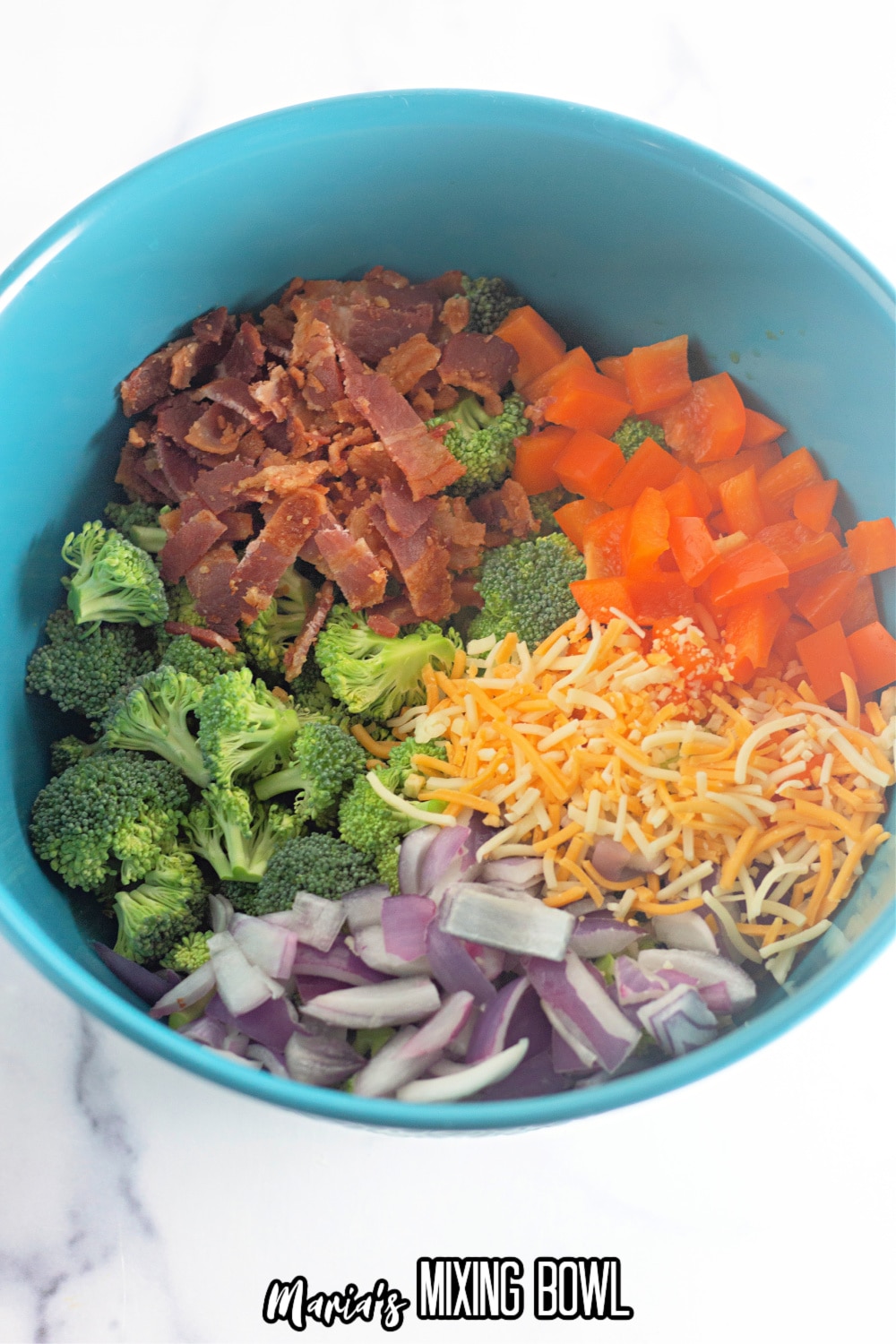 broccoli, peppers, cheese, onions, and bacon in a blue mixing bowl