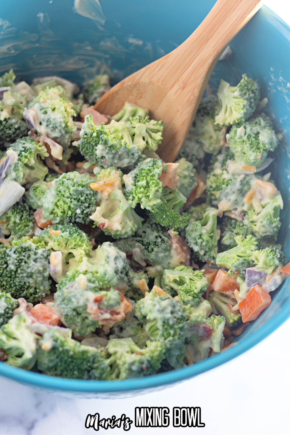 finished broccoli salad in a blow mixing bowl with a wooden spoon