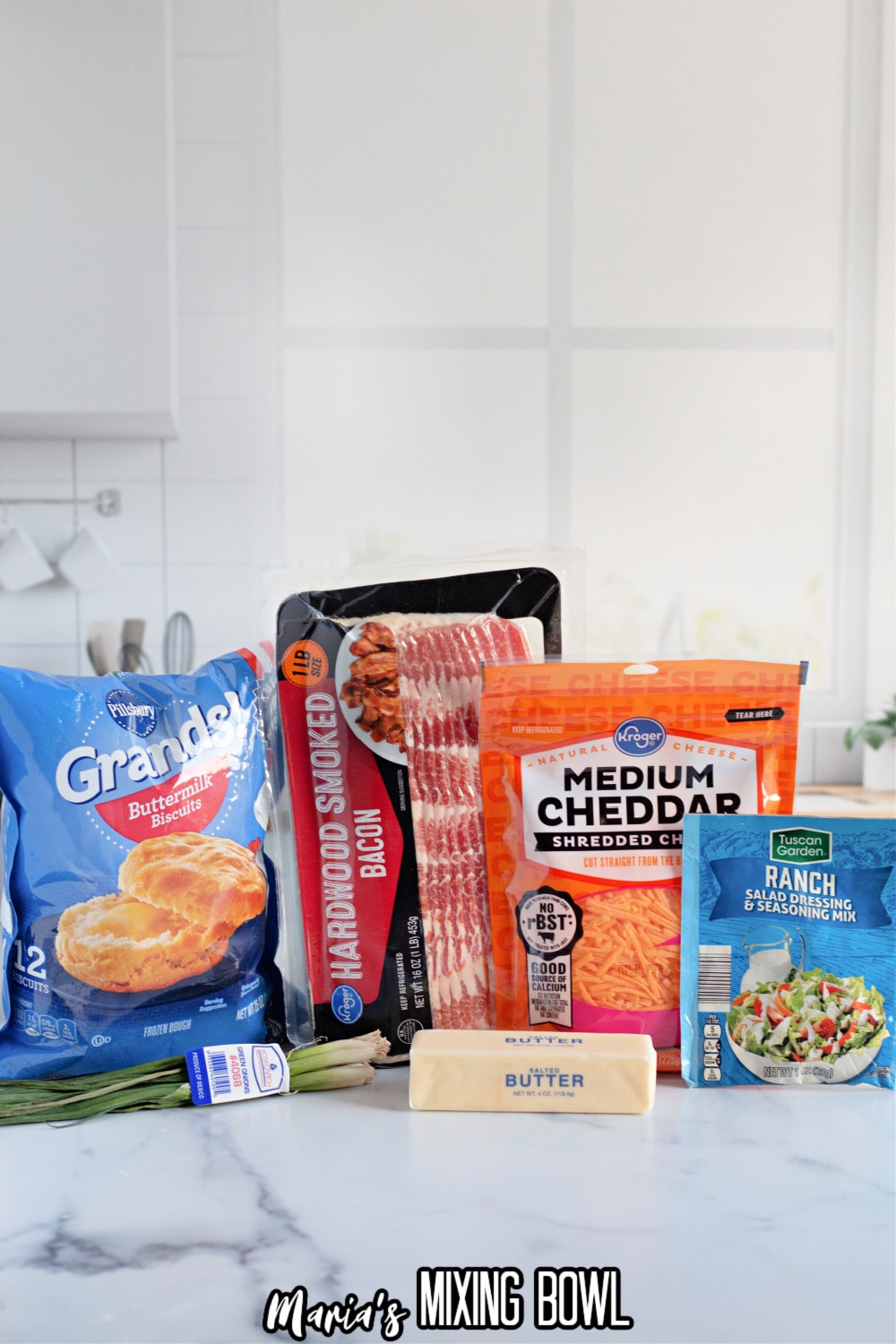 bags of frozen biscuits, bacon, medium cheddar cheese, ranch seasoning packet, stick of butter, and green onions