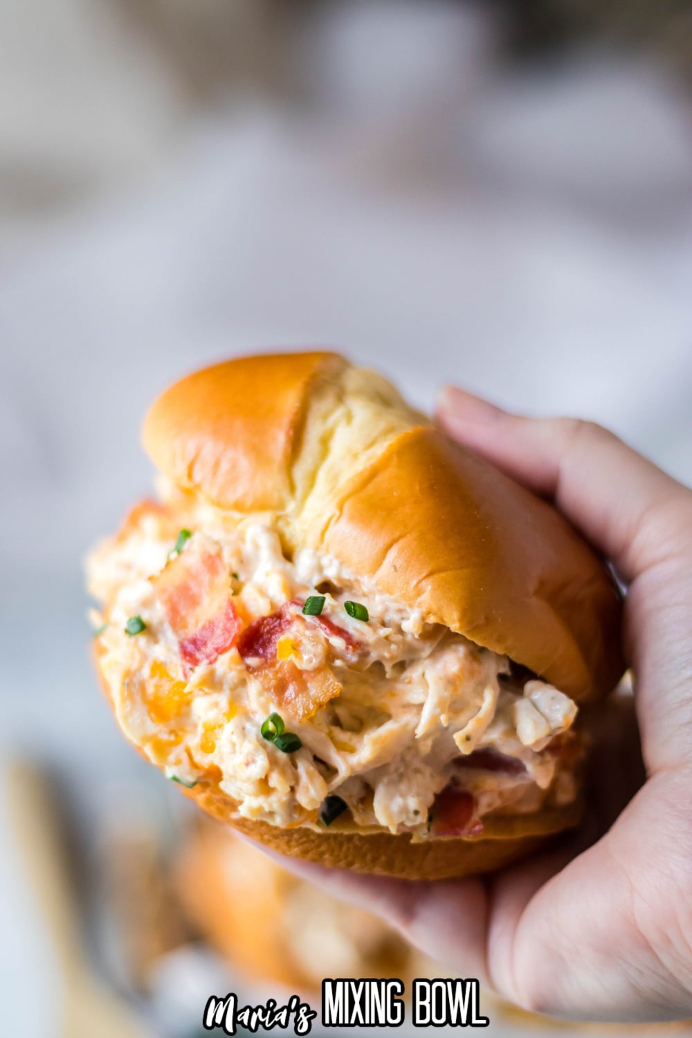 chicken bacon ranch sandwich held in a womans hand in the air