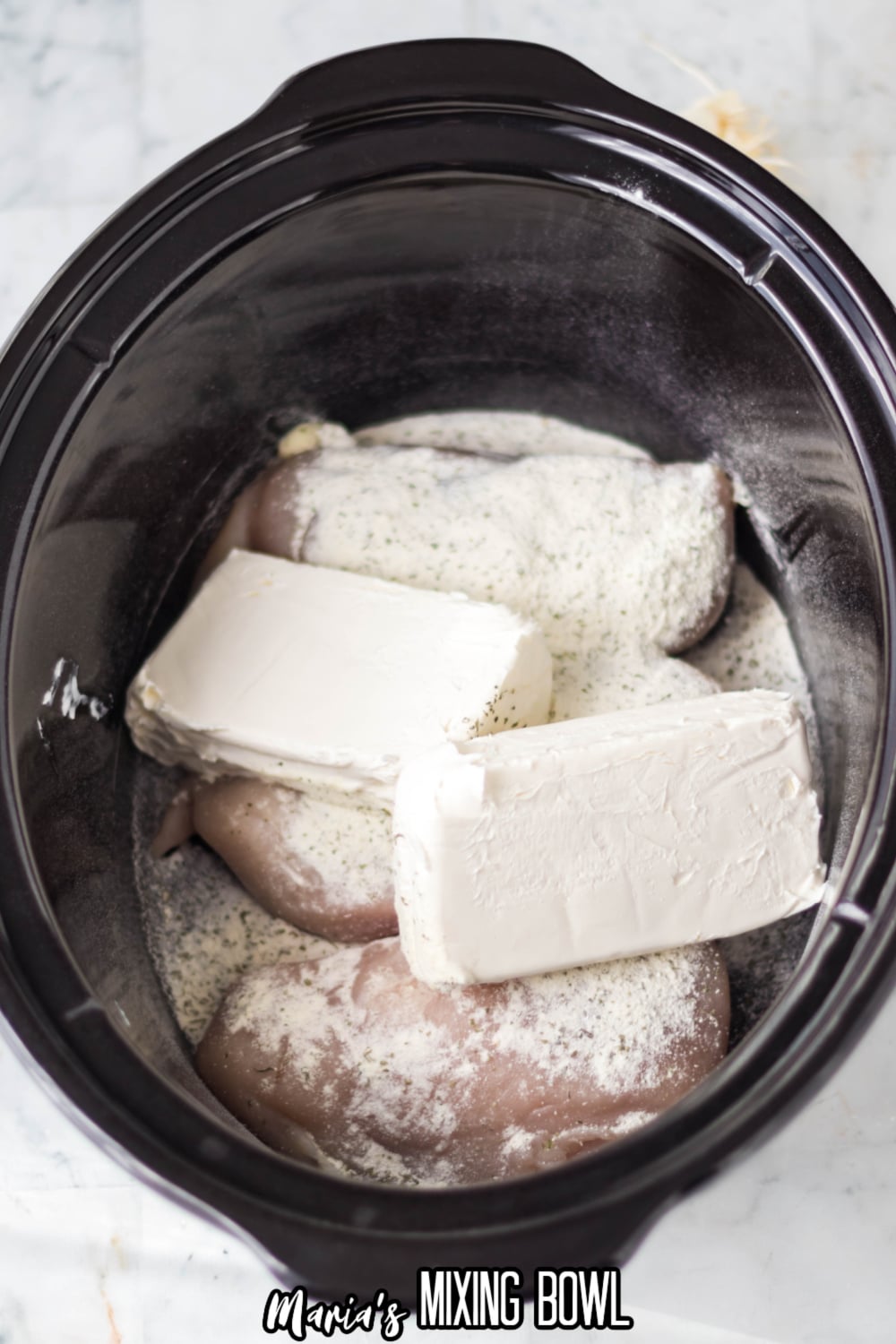 cream cheese, chicken and ranch seasoning in a black slow cooker