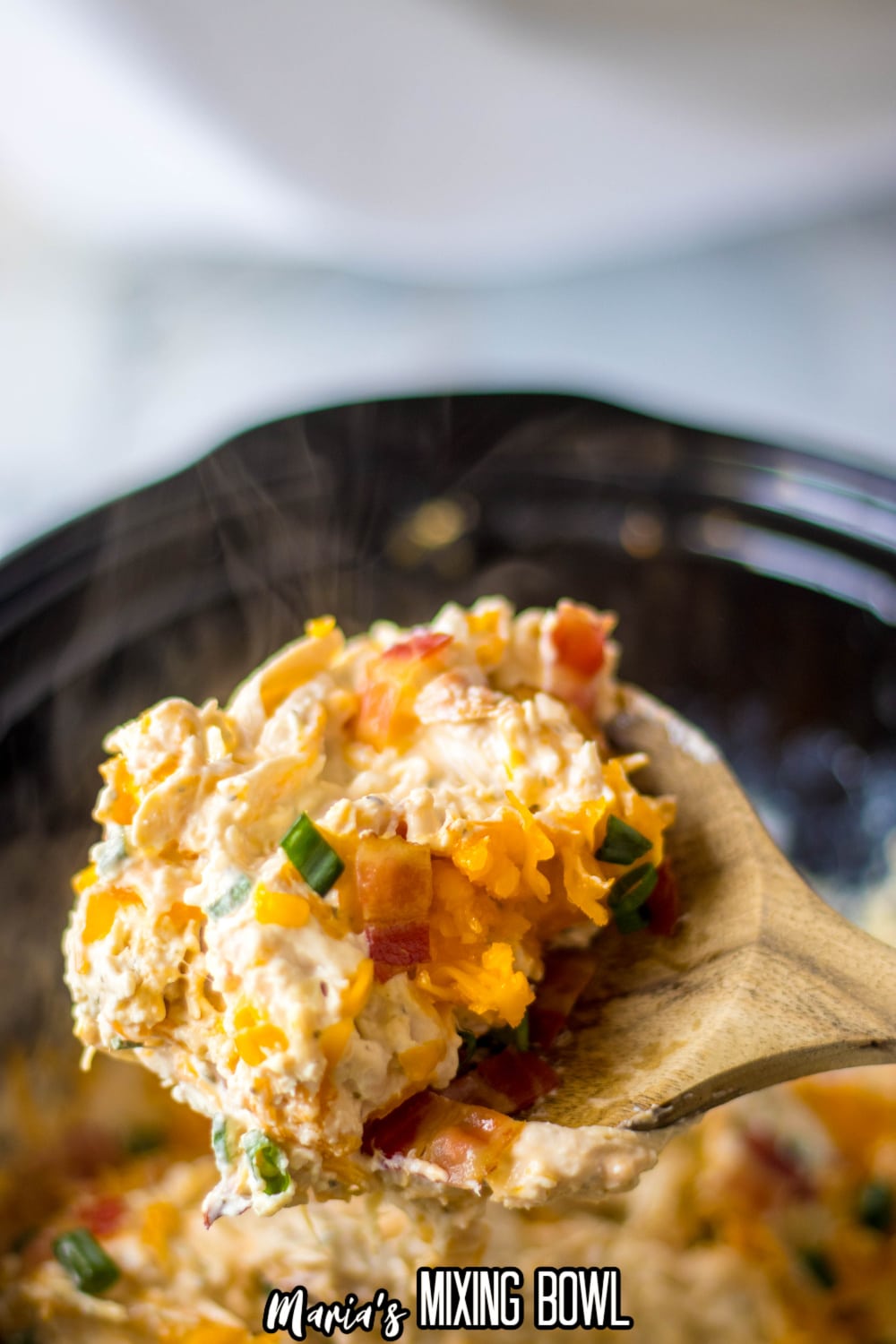 wooden spoon full of chicken bacon ranch mixture held in the air above the slow cooker