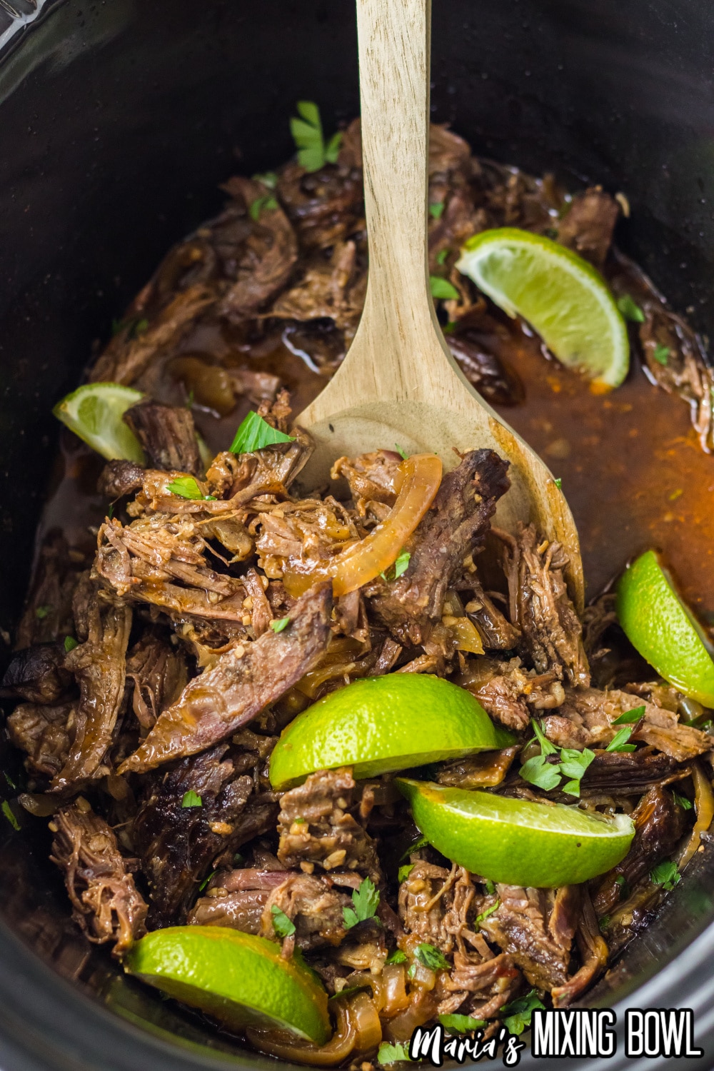copycat chipotle barbacoa in a slow cooker topped with lime wedges
