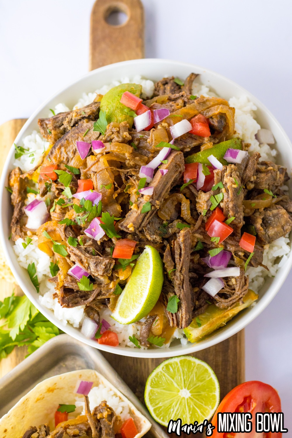 bowl of white rice topped with barbacoa and diced onions and diced tomatoes