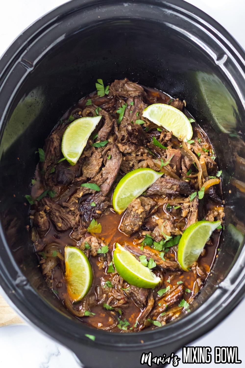 copycat chipotle barbacoa in a slow cooker topped with lime wedges