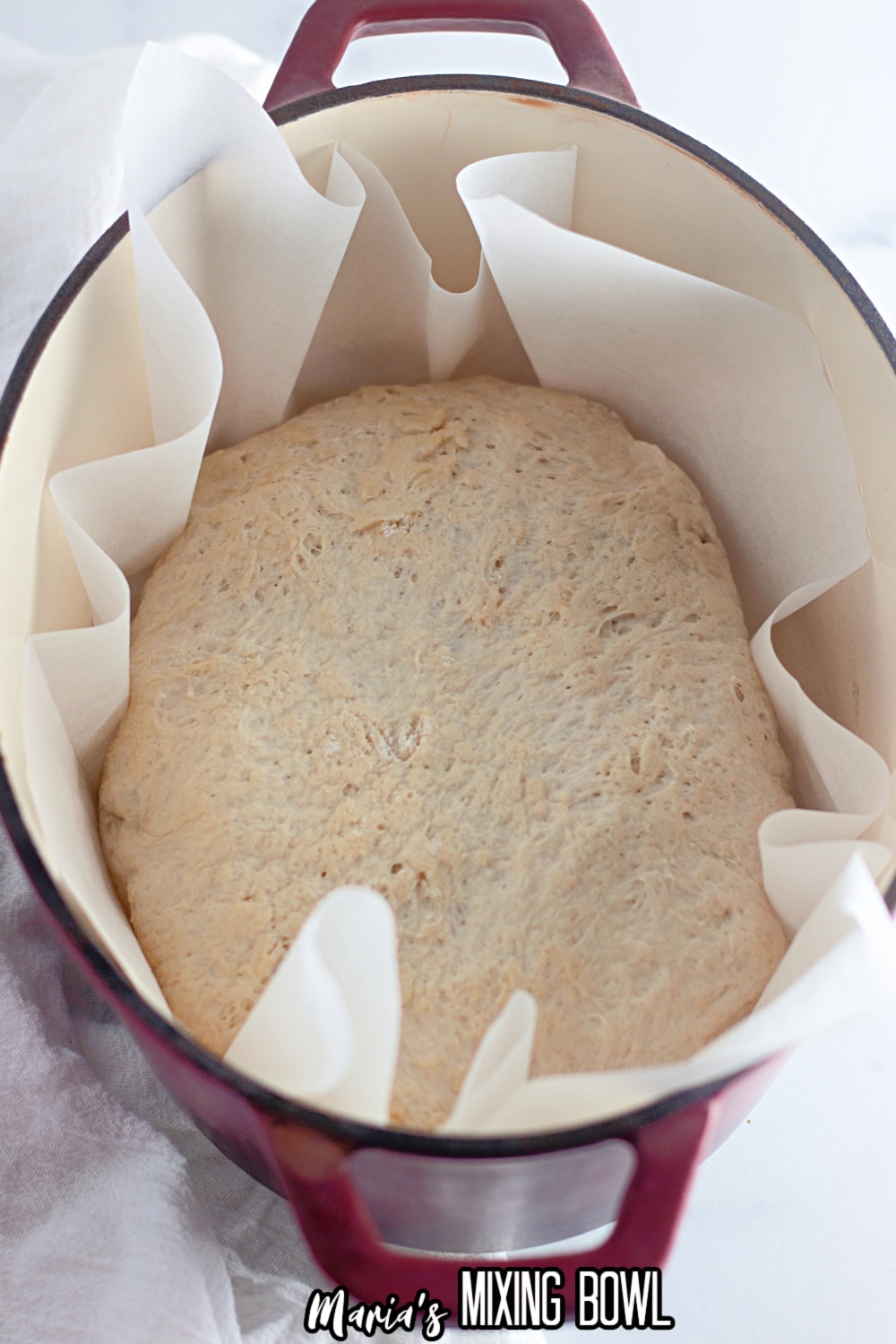 unbaked loaf of dutch oven bread in a parchment lined dutch oven
