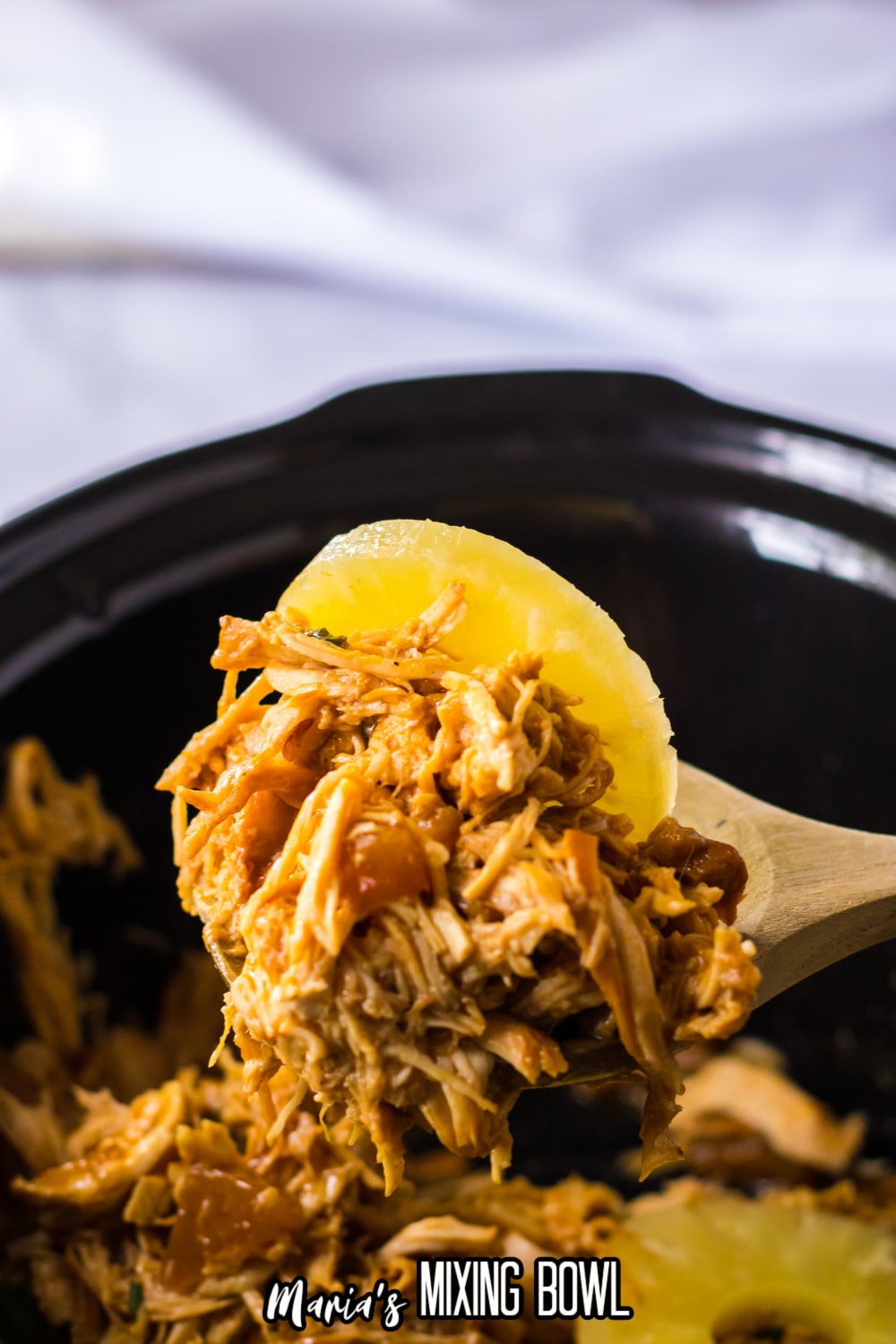 wooden spoonful shredded hawaiian chicken in a slow cooker