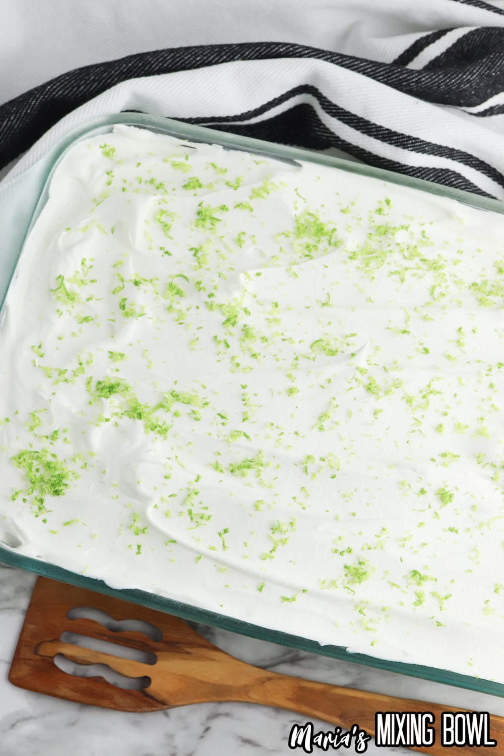 finished key lime poke cake in a glass baking dish topped with lime zest