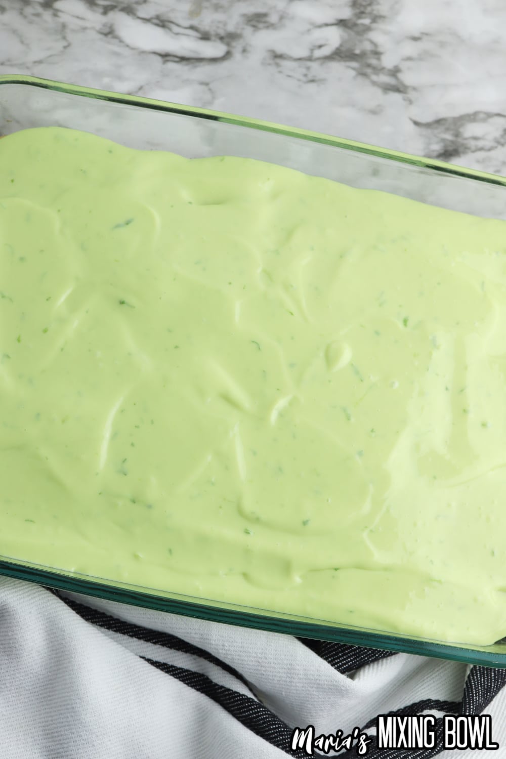 key lime filling being spread on top of a white cake in a glass casserole dish