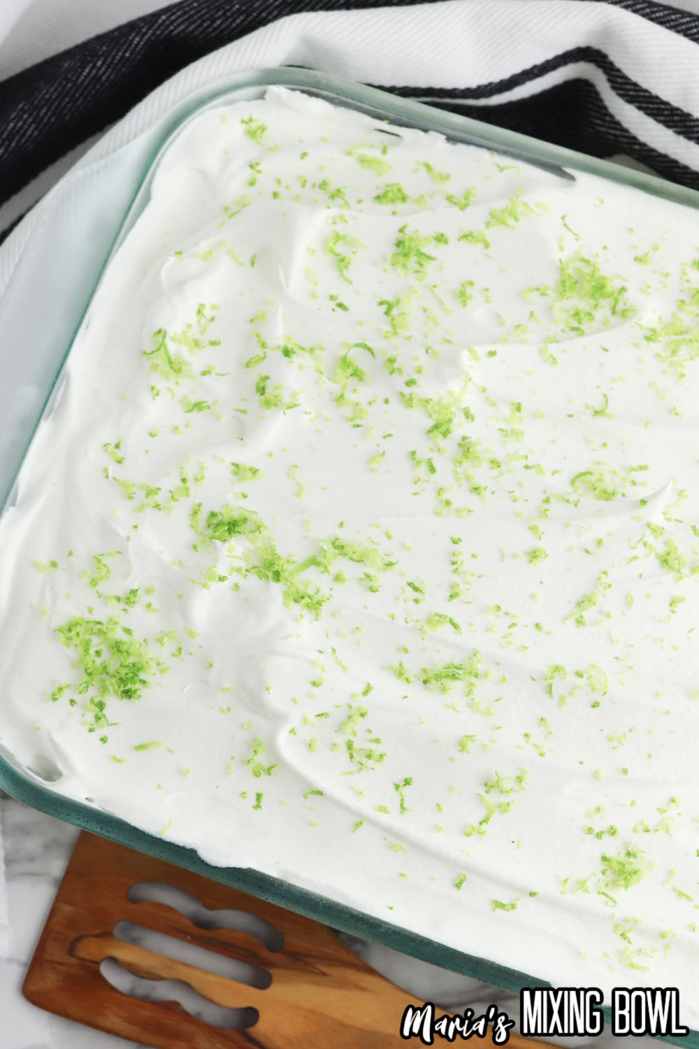 finished key lime poke cake in a glass baking dish topped with lime zest