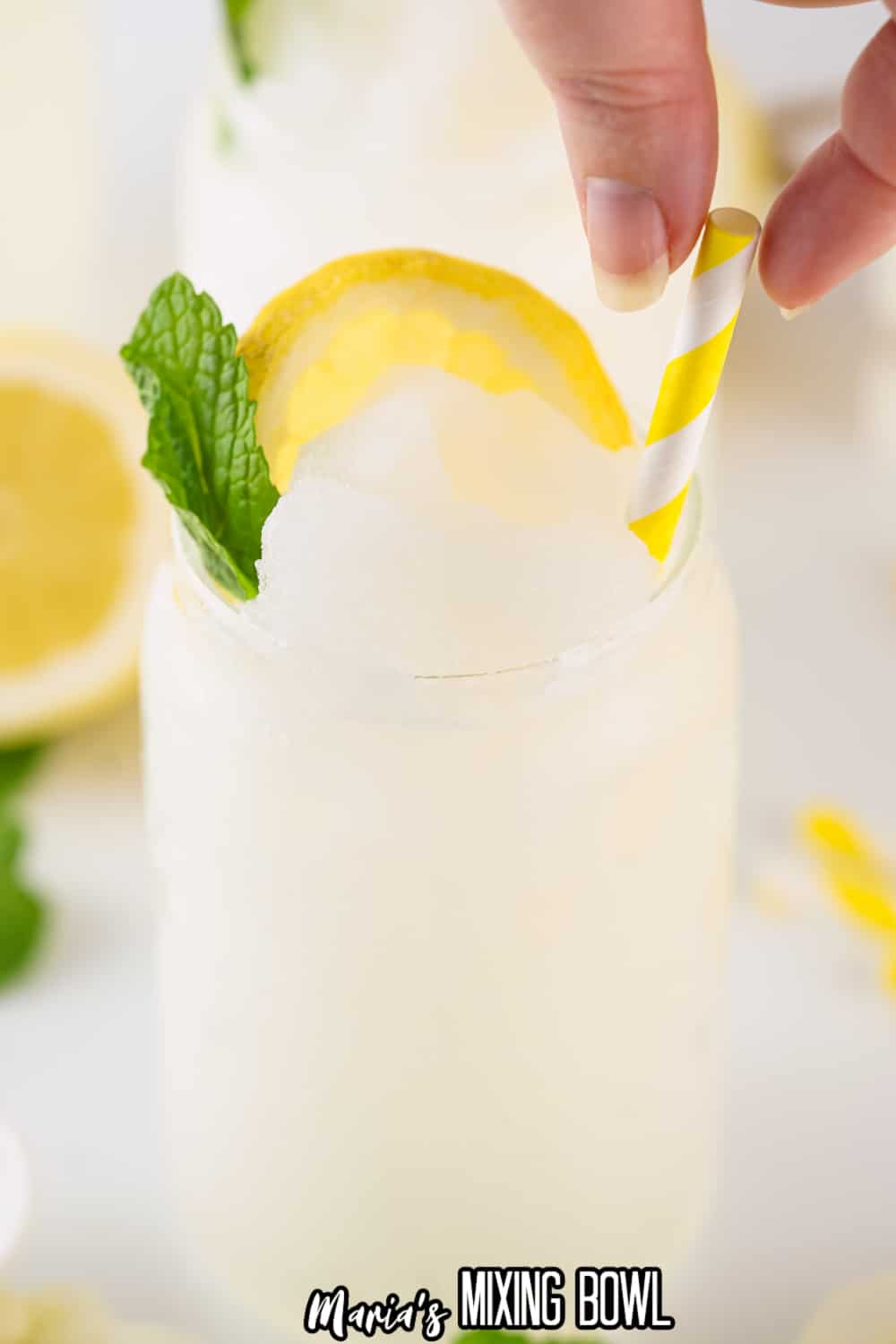 a yellow and white stripped straw being added to a glass of lemonade slushies