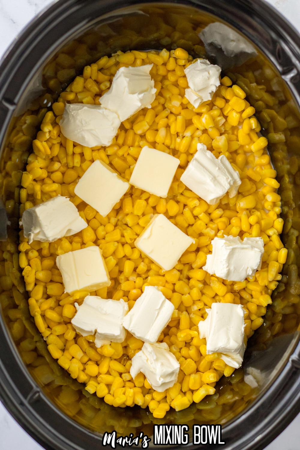 corn in a slow cooker topped with pats of butter