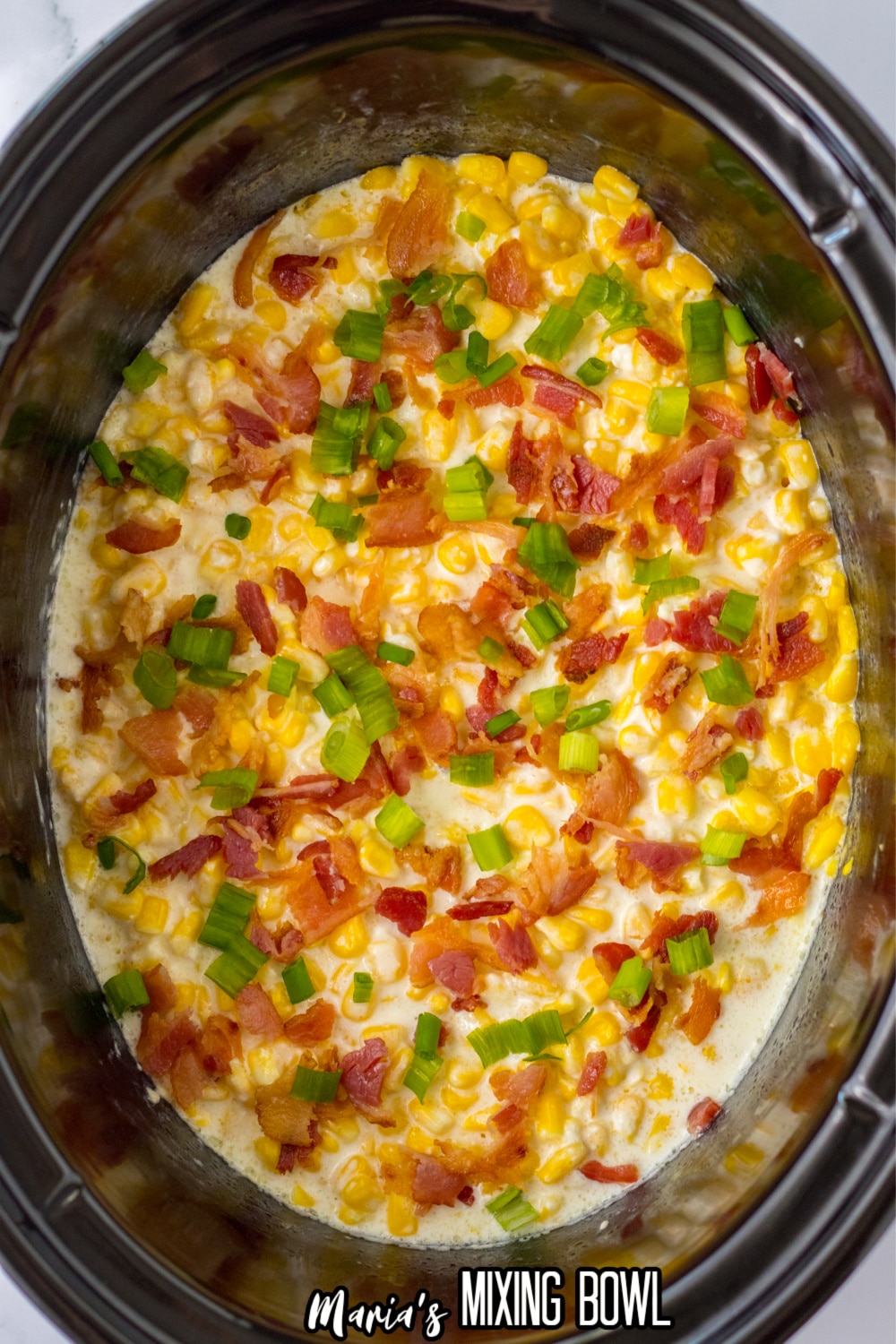 bacon, cheese and sliced green onions on top of corn in a low cooker