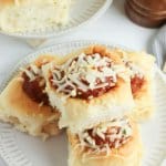 meatball sliders topped with mozzarella cheese on a white plate