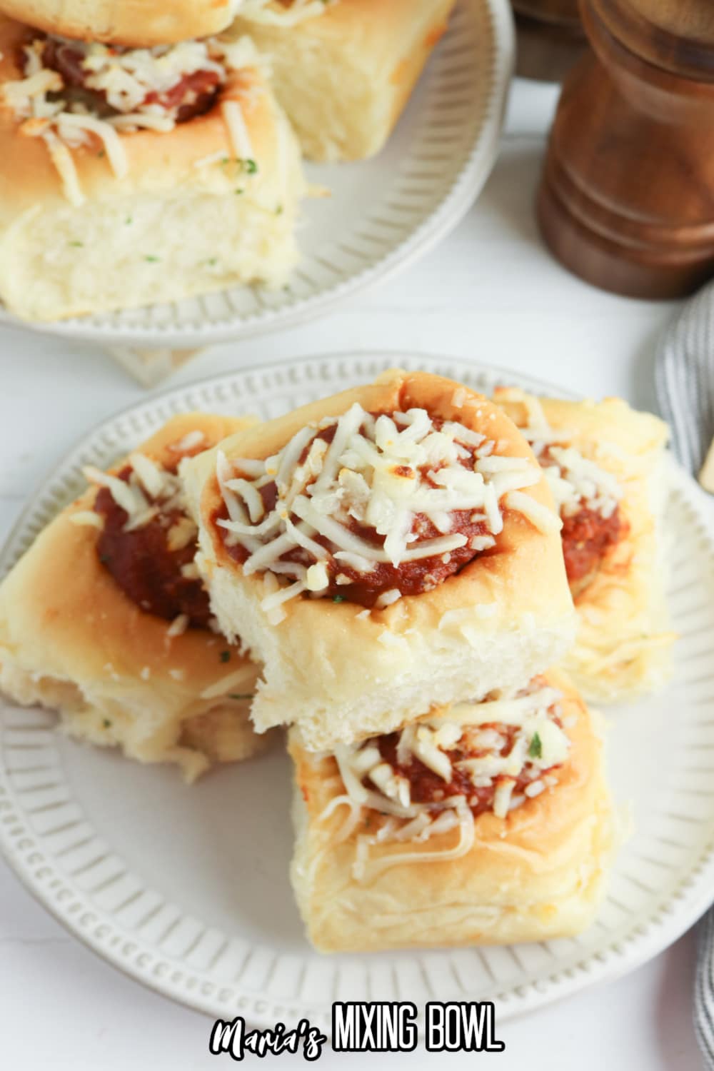 meatball sliders topped with mozzarella cheese on a white plate