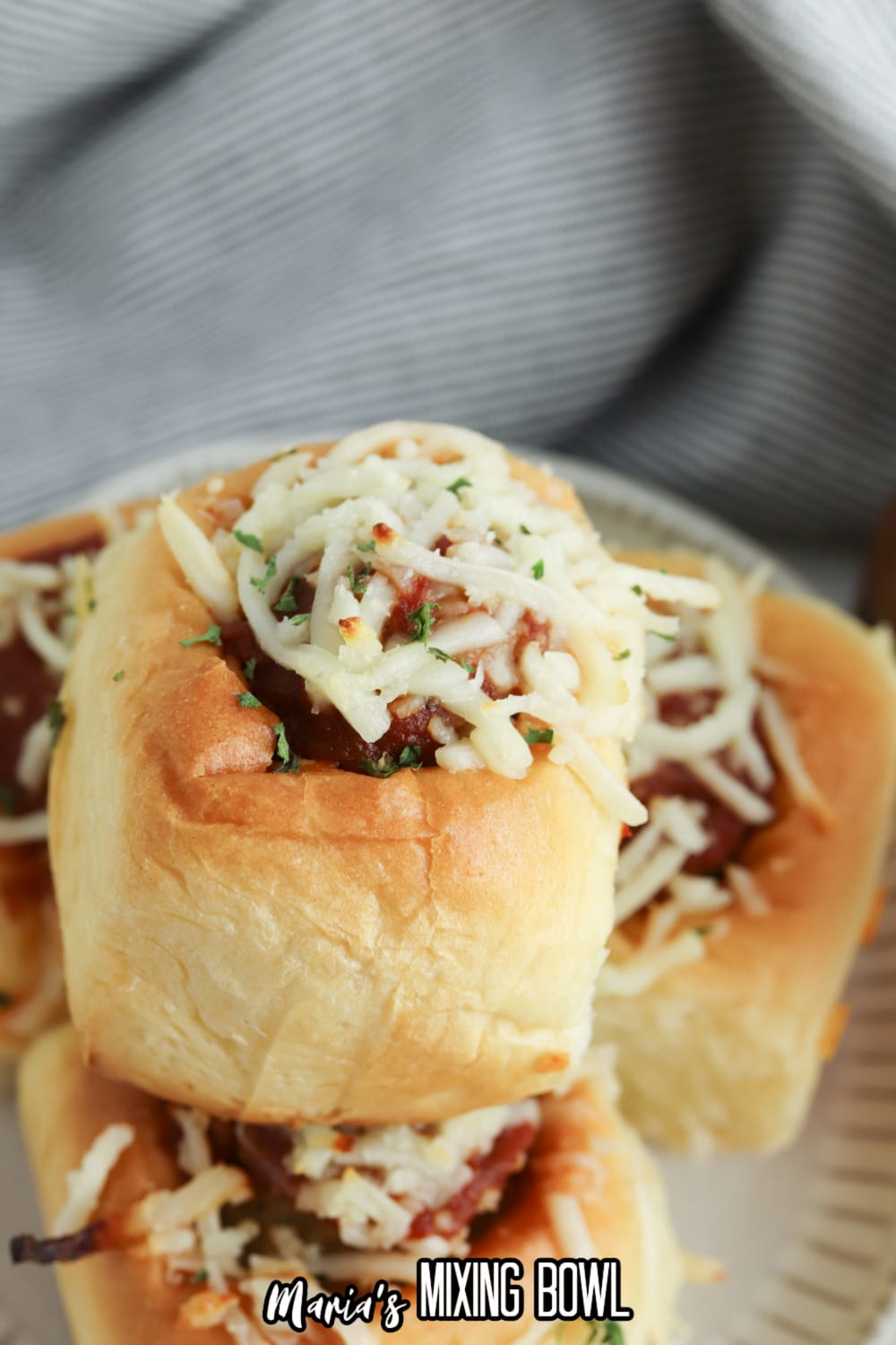 meatball sliders topped with mozzarella cheese on a white plate