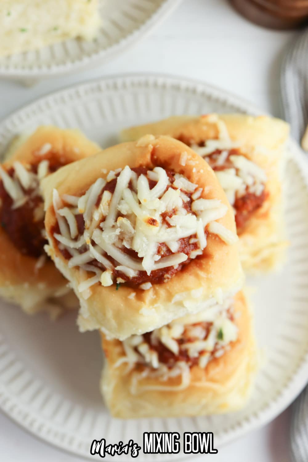meatball sliders topped with mozzarella cheese on a white plate