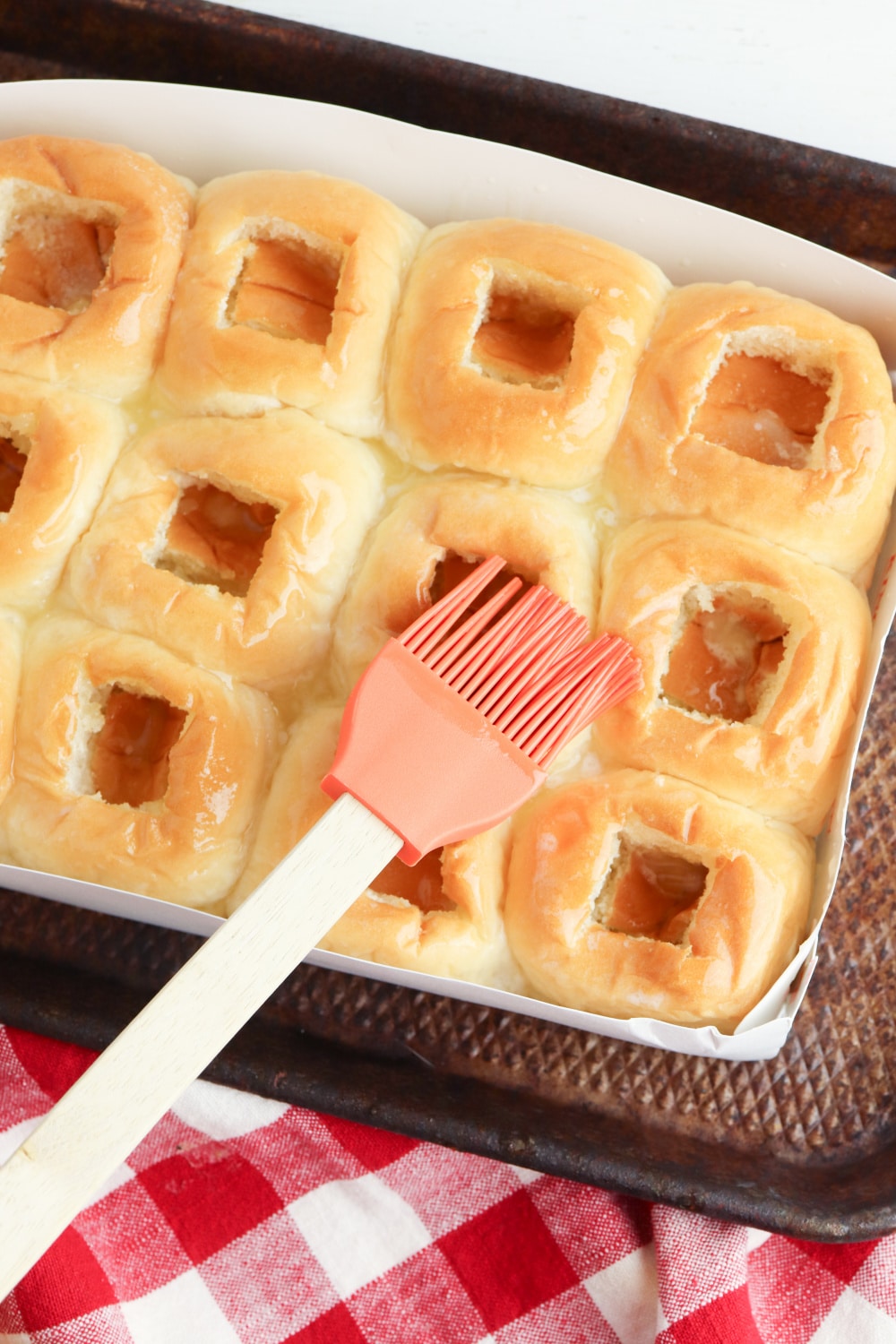 melted butter and garlic powder being brushed on top of rolls in a package