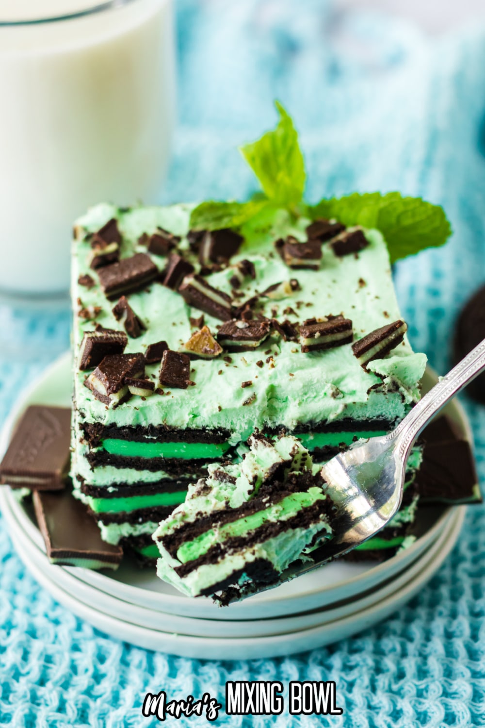 slice of mint chocolate icebox cake on a stack of small white plates with a fork with a bite on it.