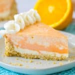 slice of orange cheesecake on a white plate on top of a bright blue kitchen towel