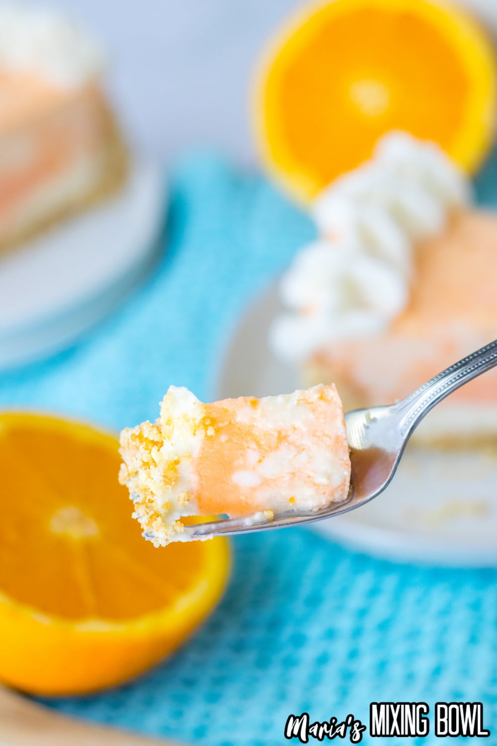 bite of orange creamsicle cheesecake held in the air on a sliver fork