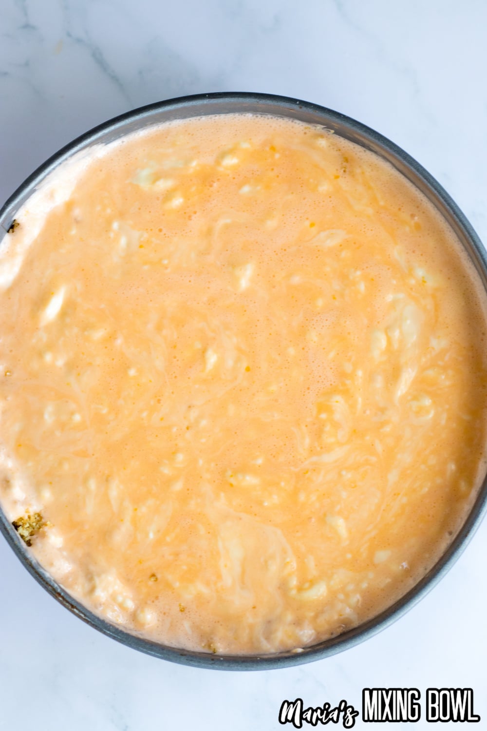 cheesecake batter poured into a springform pan on top of a graham cracker crust
