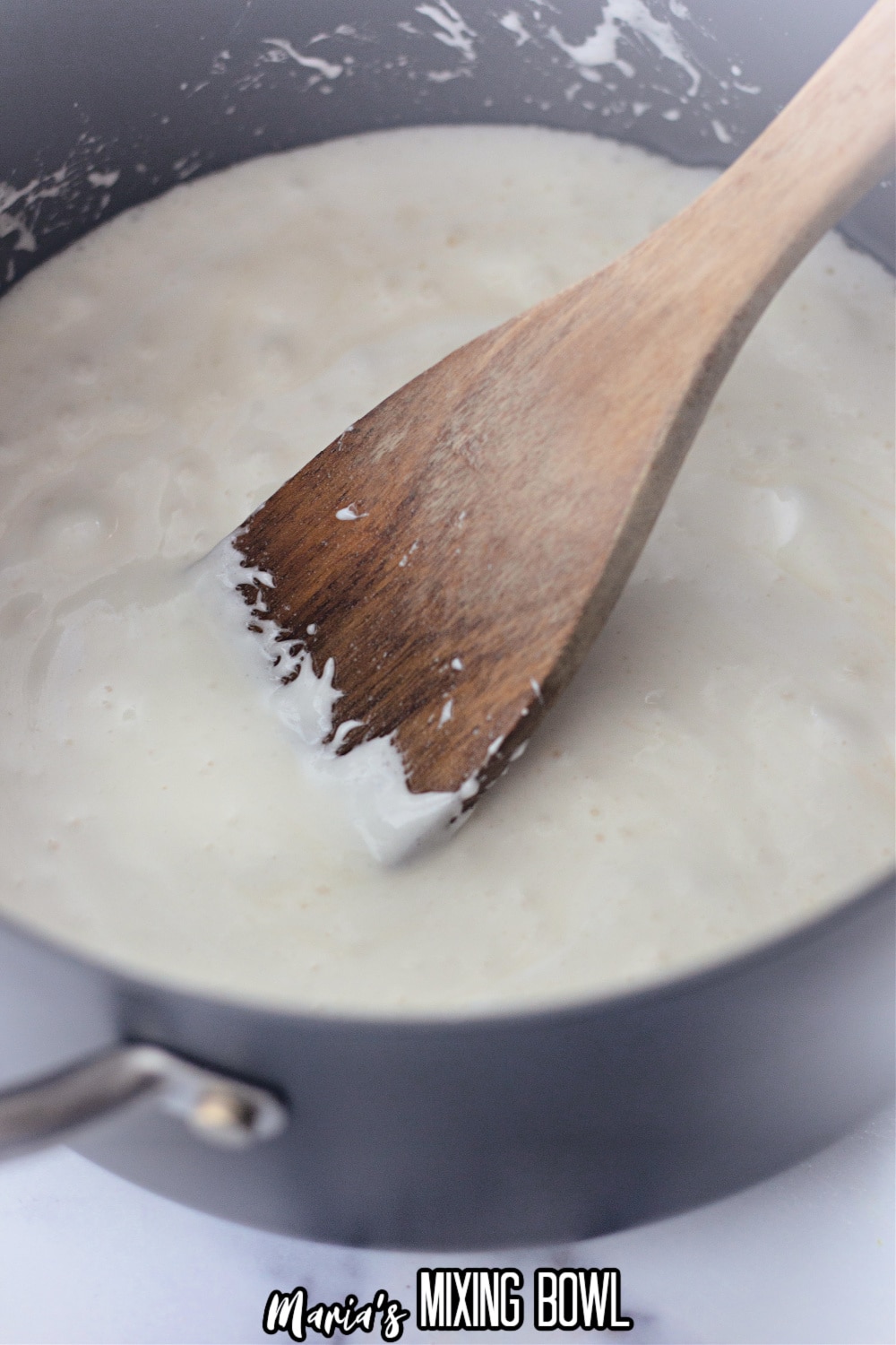 melted marshmallows and butter in a saucepan being stirred with a wooden spoon