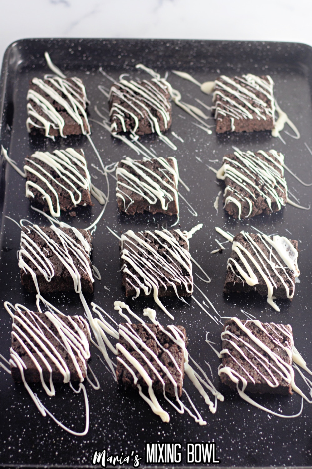 12 oreo bars drizzled with white chocolate on a dark baking sheet