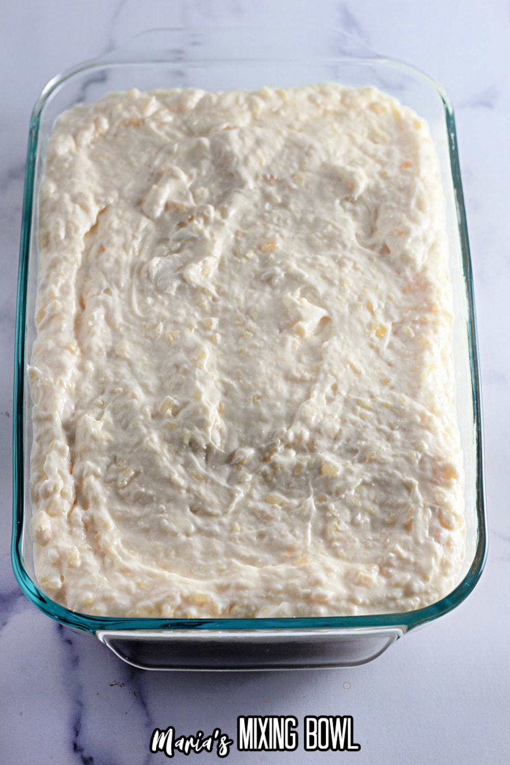 pineapple cream cheese mixture being spread into a glass baking dish