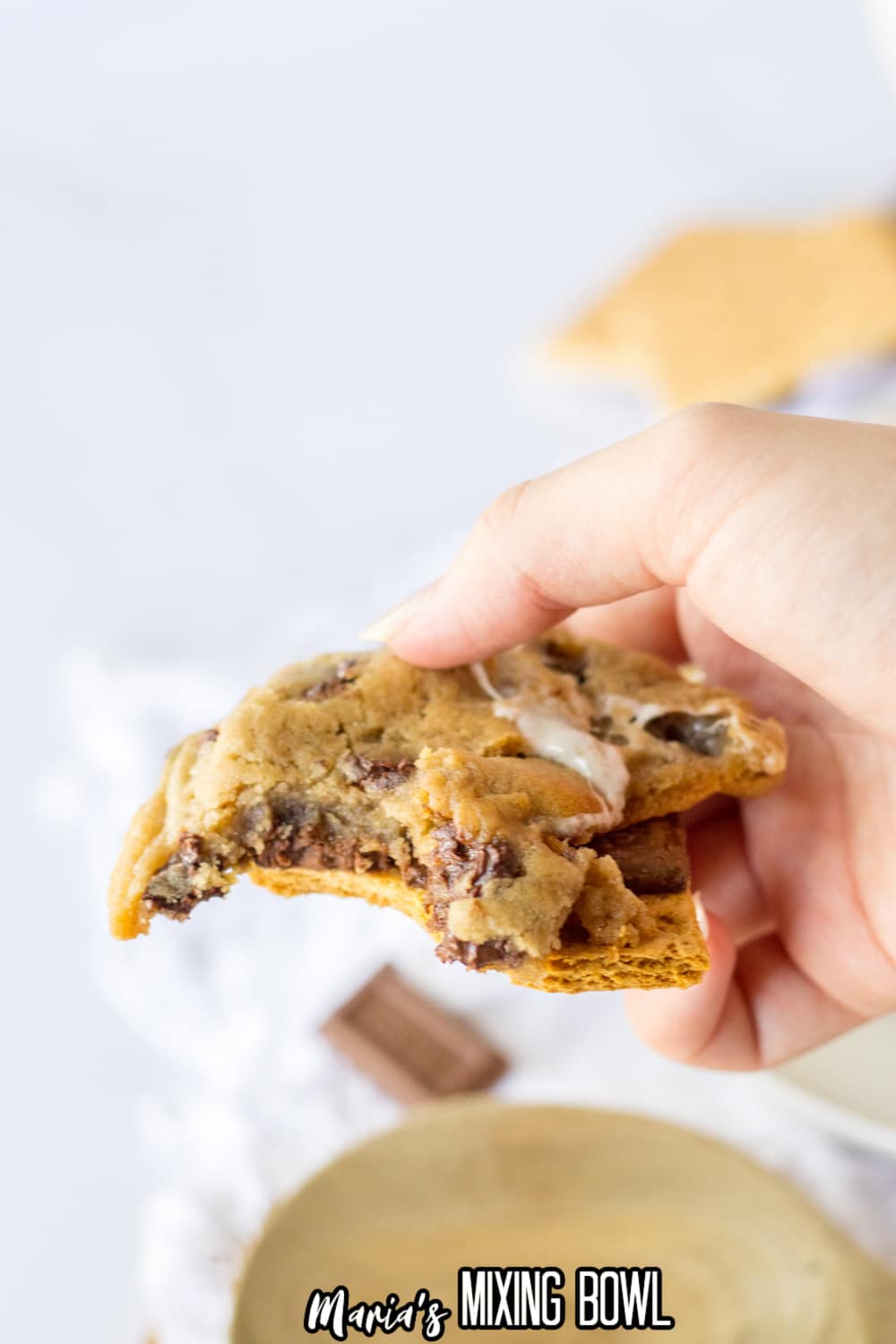 smores cookie held in a womens hand in the air.