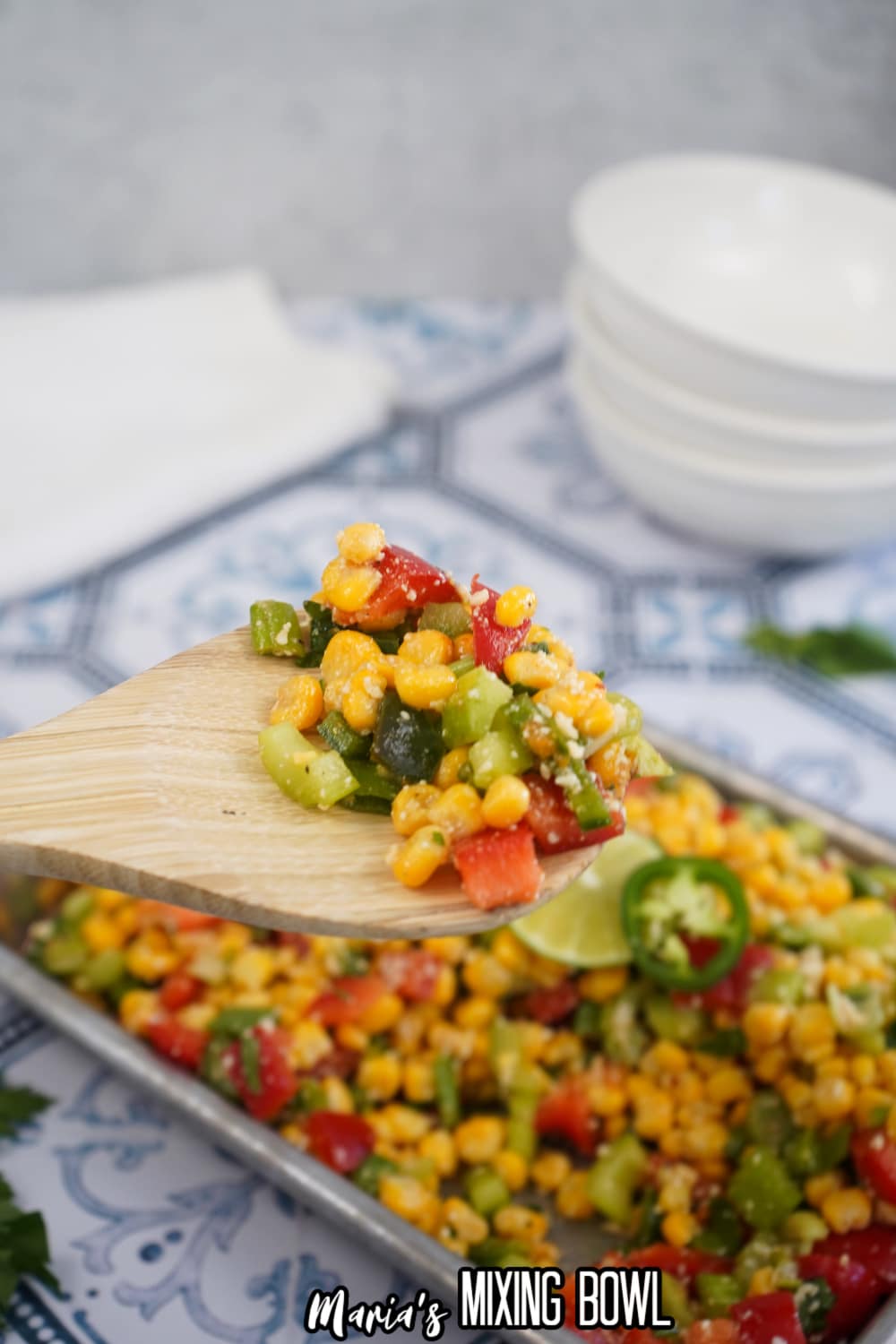 large bite of spicy corn salad on a wooden spoon held in the air