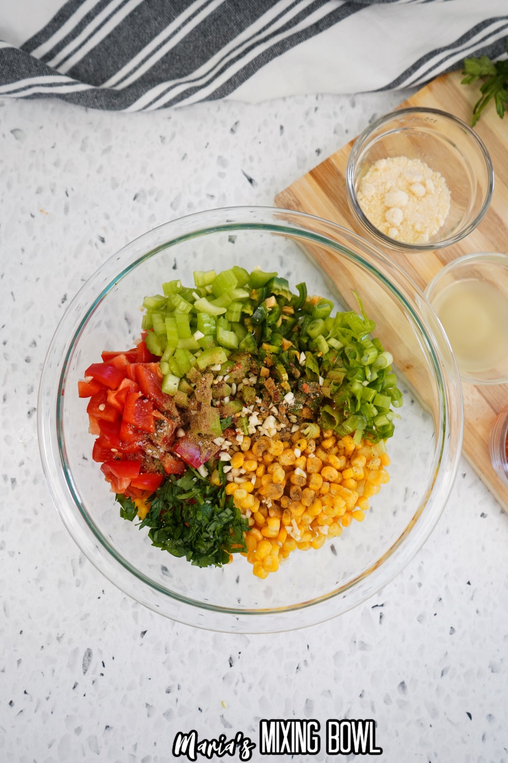 seasonings being added to the corn salad in a mixing bowl
