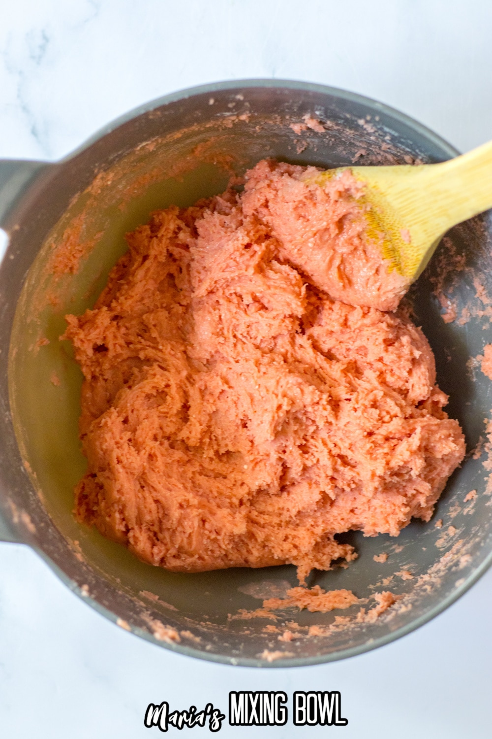 strawberry cake mix in a stainless steel mixing bowl with a wooden spoon 