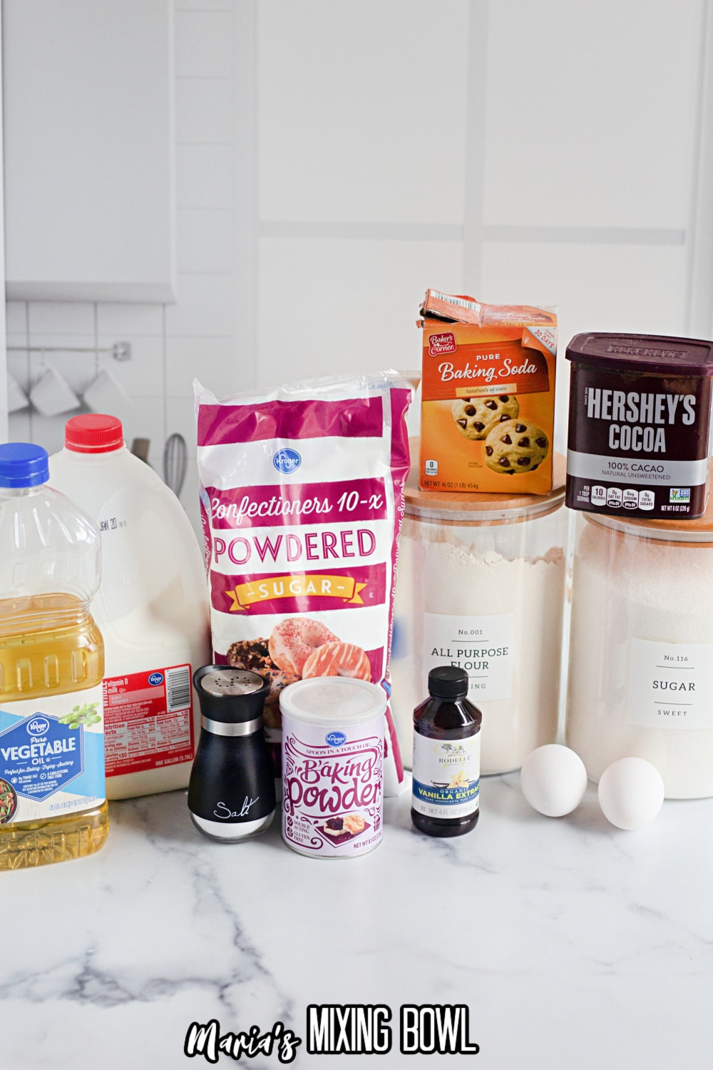 milk, oil, powdered sugar, baking soda, cocoa powder, all purpose flour, sugar, eggs, vanilla extract, baking power and salt on a marble background