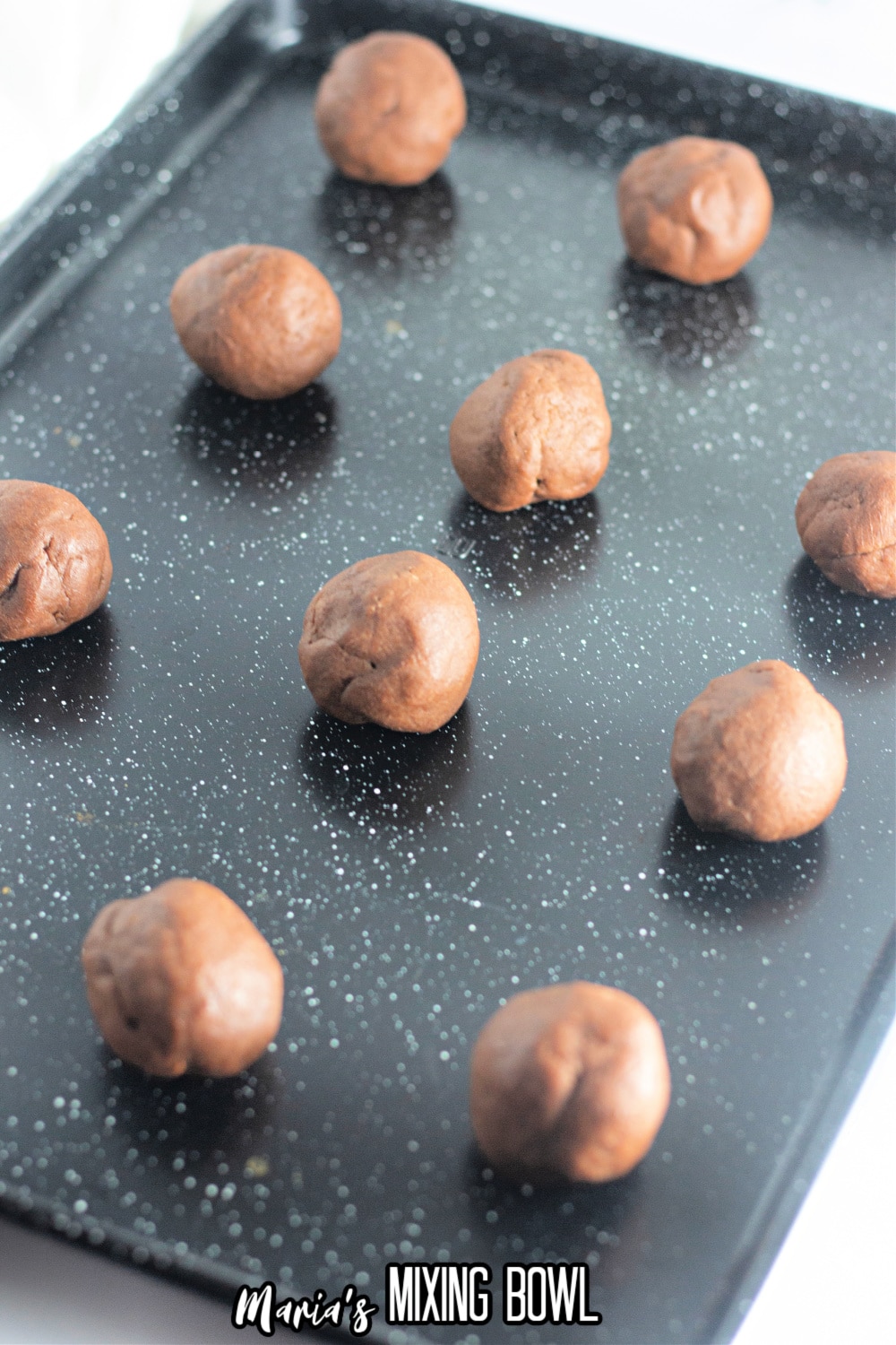 chocolate cookie dough balls on a dark baking sheet