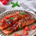 two salmon filets on a plate topped with sesame seeds and fresh parsley.