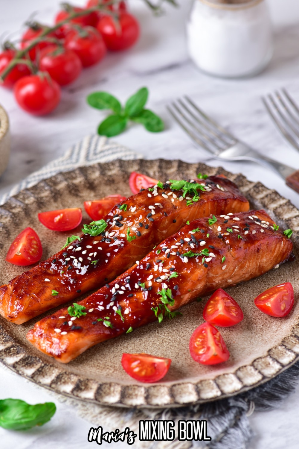 two salmon filets on a plate topped with sesame seeds and fresh parsley.