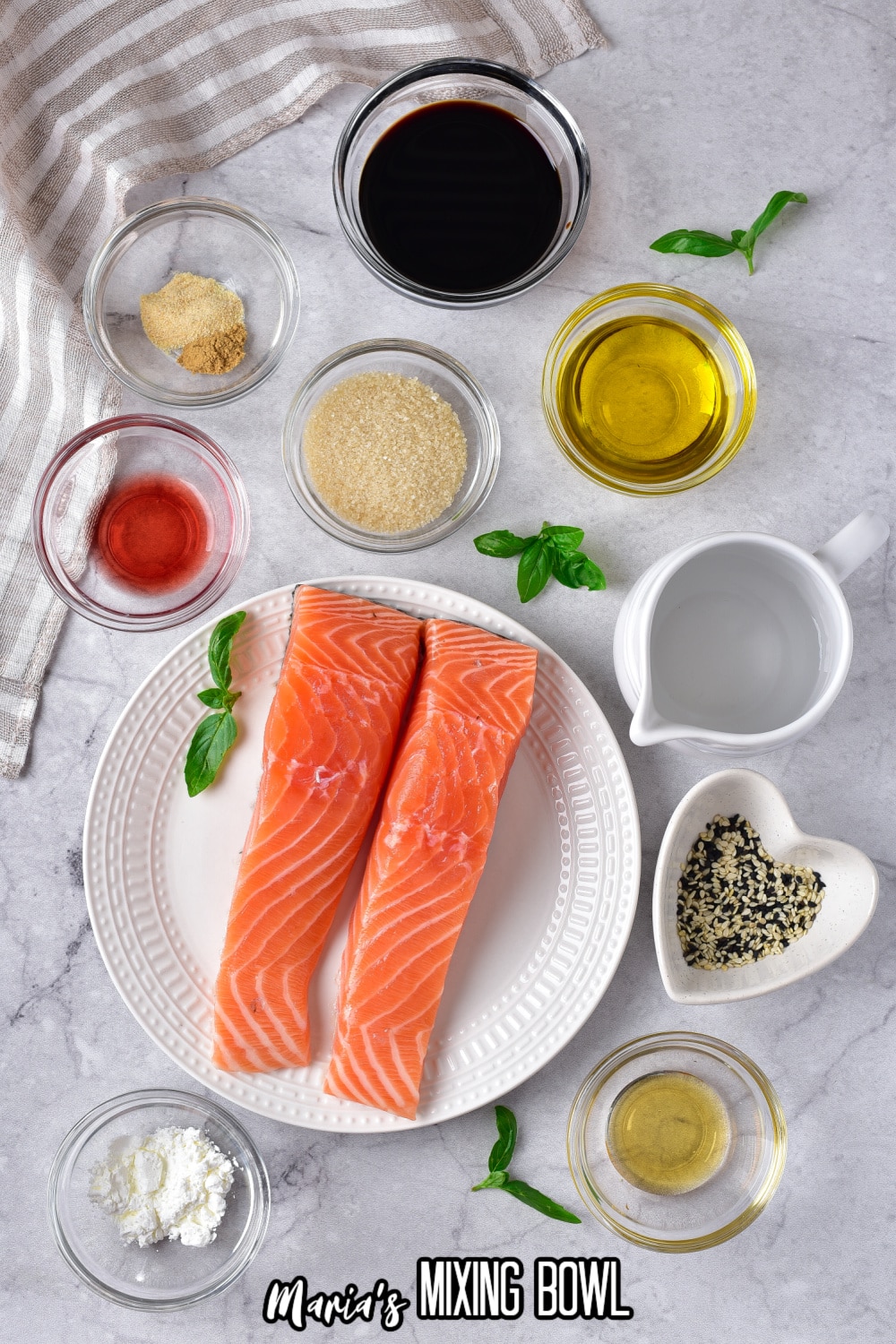 bowls of soy sauce, honey, garlic, salt, pepper, ginger, vinegar, and cornstarch around a plate with two salmon filets.