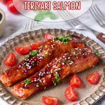 two salmon filets on a plate topped with sesame seeds and fresh parsley.