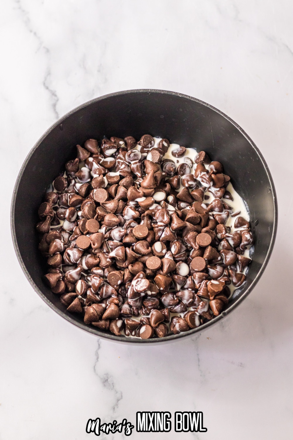 chocolate chips and heavy cream in a dark colored mixing bowl