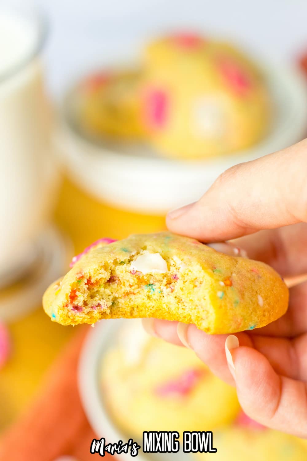 cookie held in a woman's hand with a bite taken out of it.