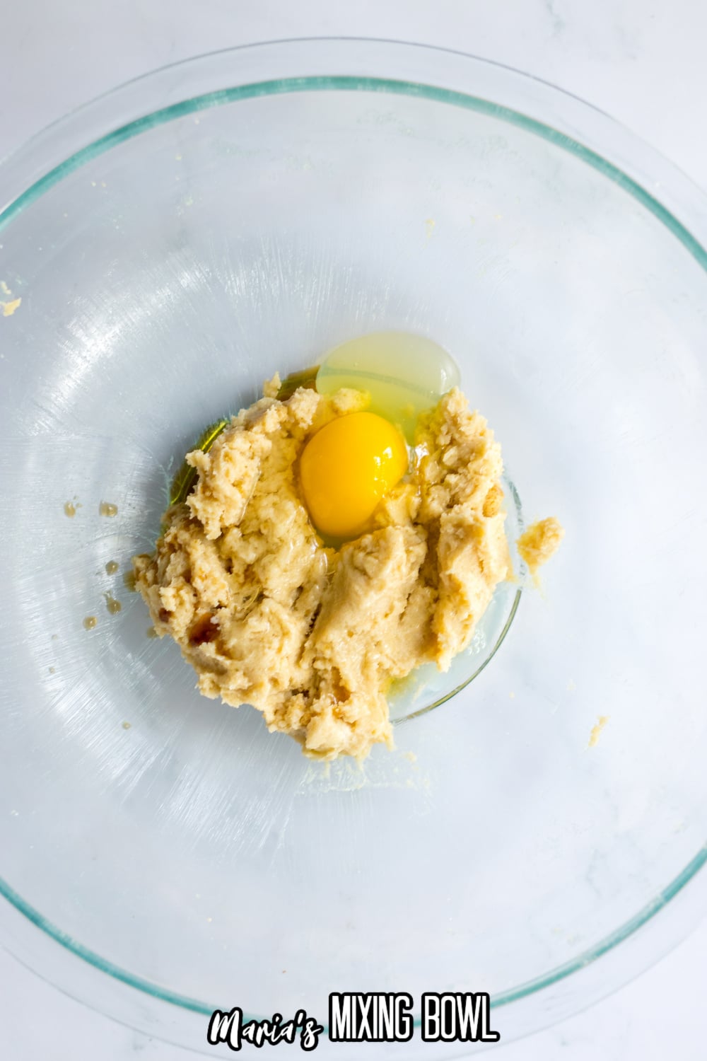 raw egg and vanilla extract being added to a bowl that has a brown sugar and butter mixture in it.