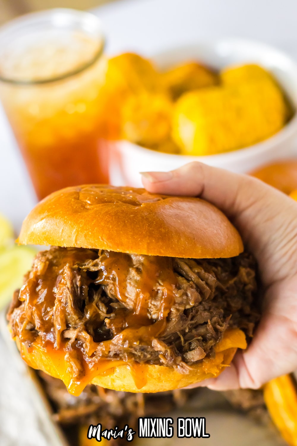 shredded beef sandwich held in the air in a woman's hand.